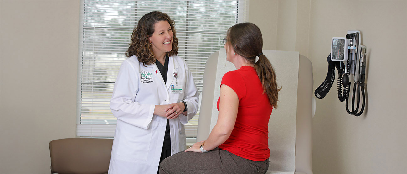 A smiling doctor speaking with a patient in an examination room.