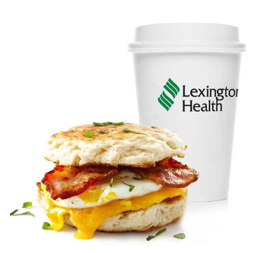 An english muffin egg, bacon and cheese sandwich with a Lexington Health branded coffee cup.