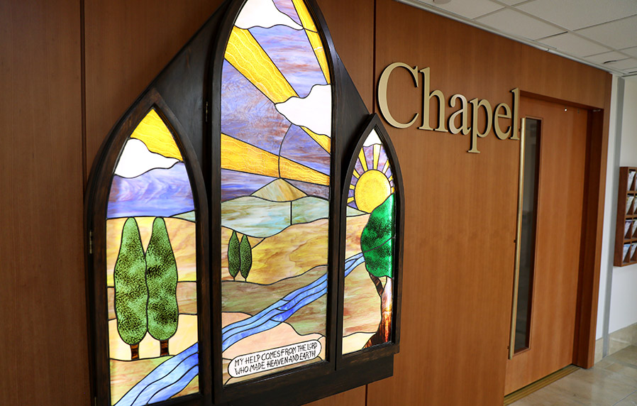 The chapel at the hospital. A stained glass of a meadow and a shining sun decorates the front of the chapel.