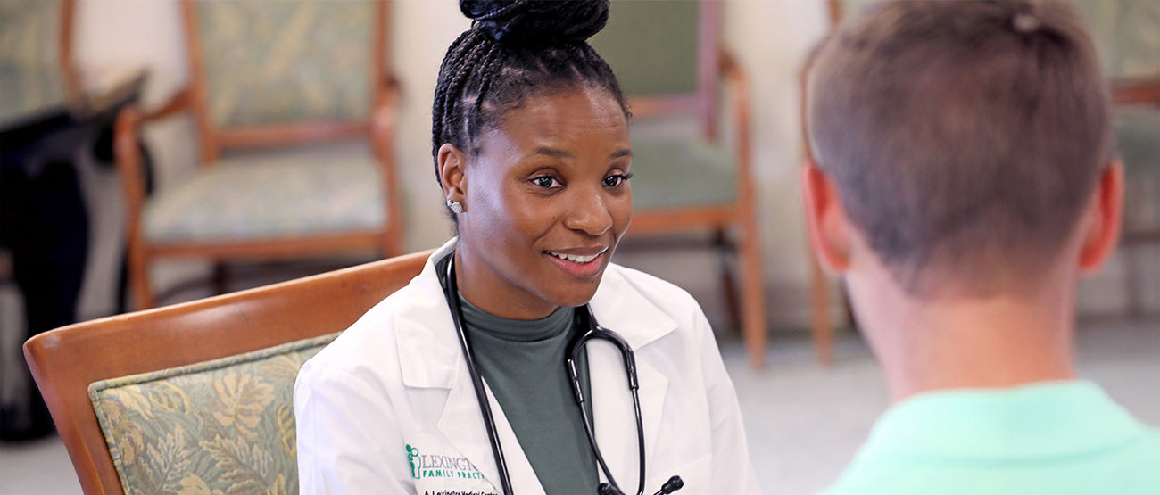 A female doctor speaking with a visitor in a waiting area.
