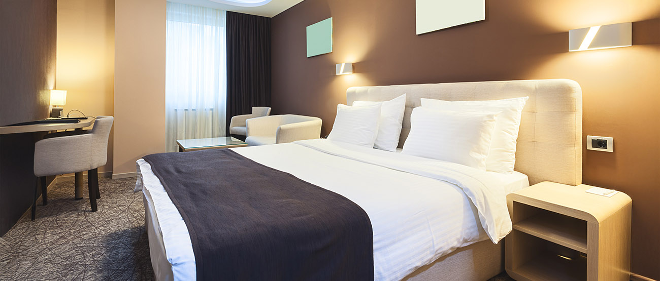 The inside of a clean hotel room with a freshly made bed.