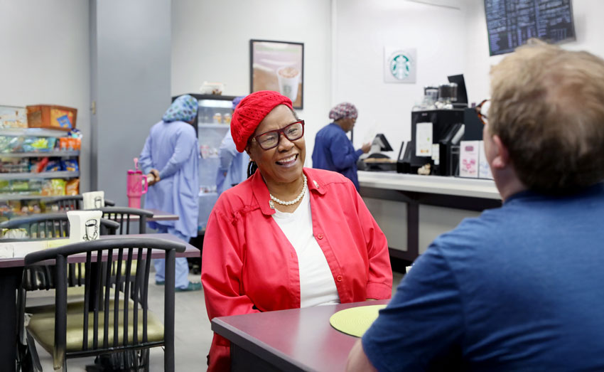 A smiling woman sitting with someone at the Park Cafe.
